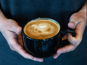 Person Holds Latte with Pattern in Froth