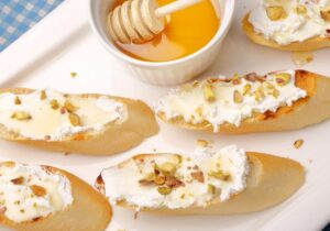 Baguette Slices Topped with Chevre, Honey, and Topped Pistachios