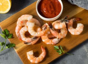 Cooked Shrimp on a Wooden Plate with Cocktail Sauce