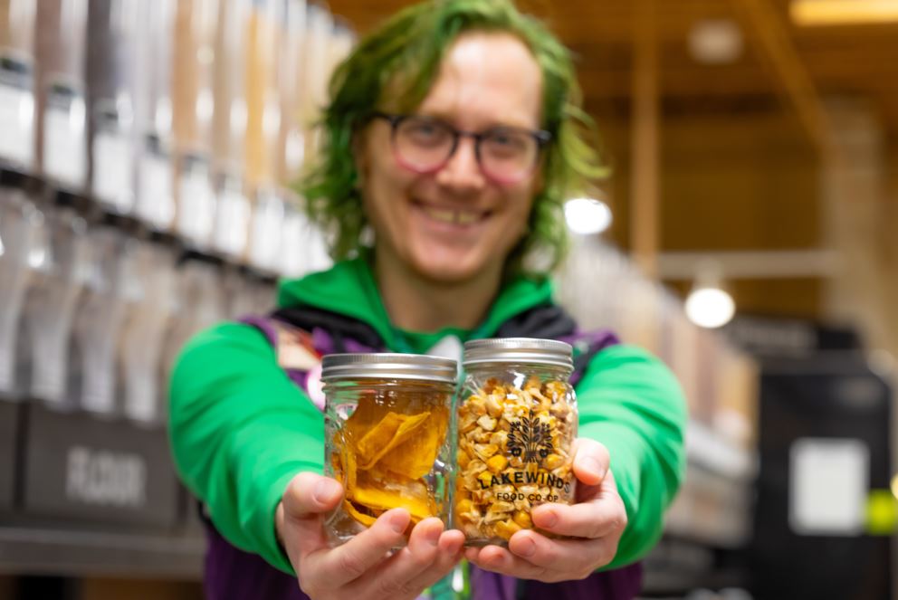 Employee Joker Holds Jars of Dried Mango and Glad Corn